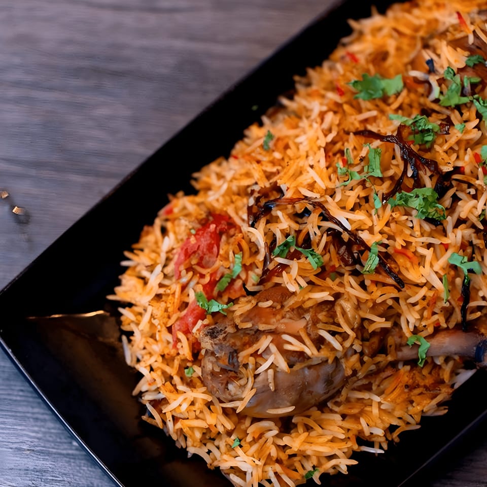 A close-up of Kolachi Kitchen's chicken biryani, garnished with fried onions and fresh cilantro.