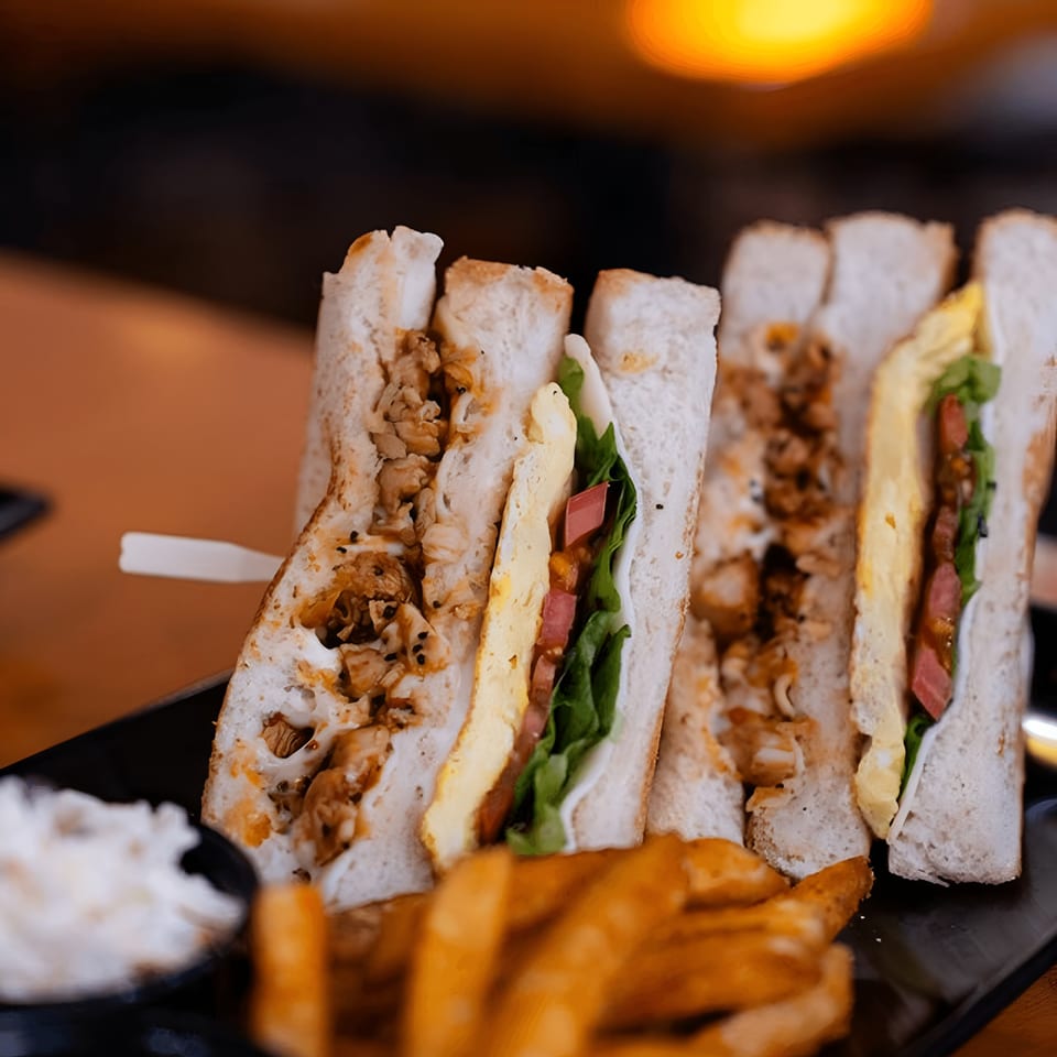 Club sandwiches with chicken, egg, lettuce, and tomato, served with fries and coleslaw.